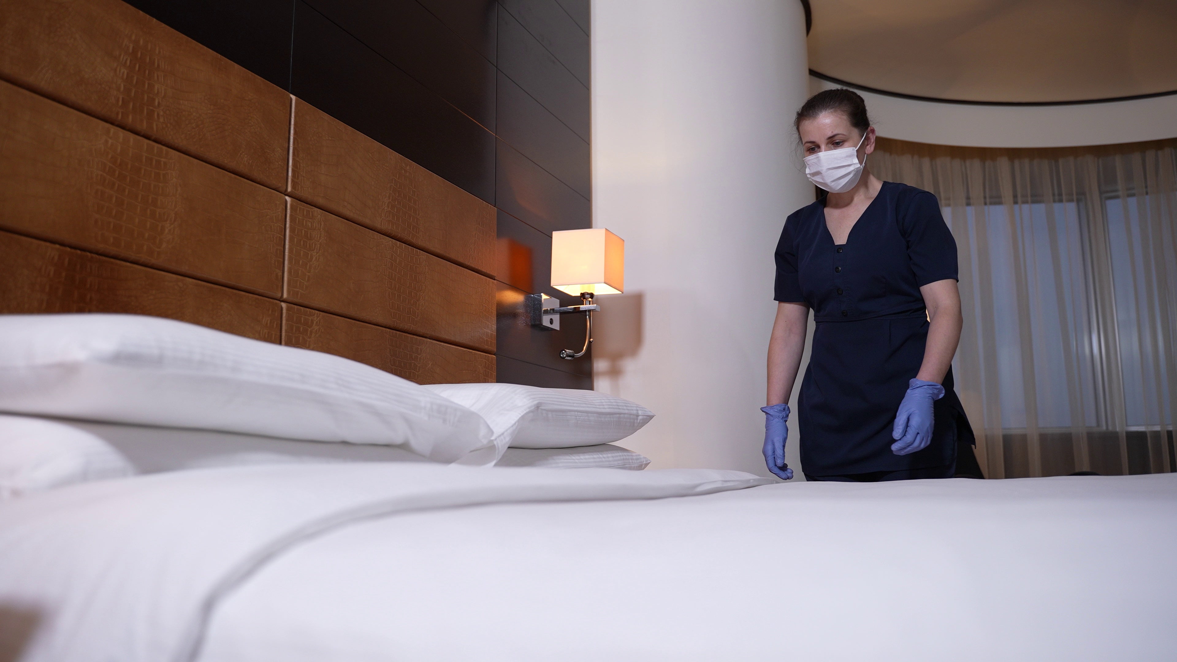 Housekeeper finishing making hotel bed